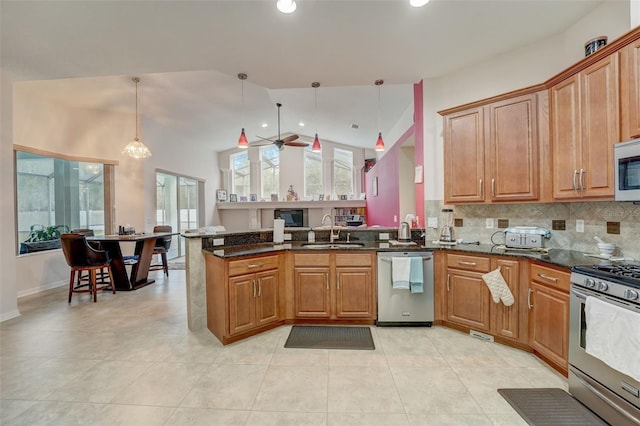 kitchen featuring dark stone counters, sink, hanging light fixtures, appliances with stainless steel finishes, and kitchen peninsula