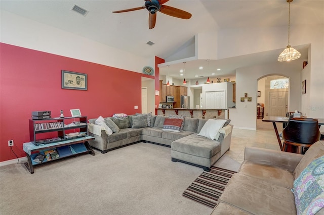 living room featuring ceiling fan, high vaulted ceiling, and light carpet