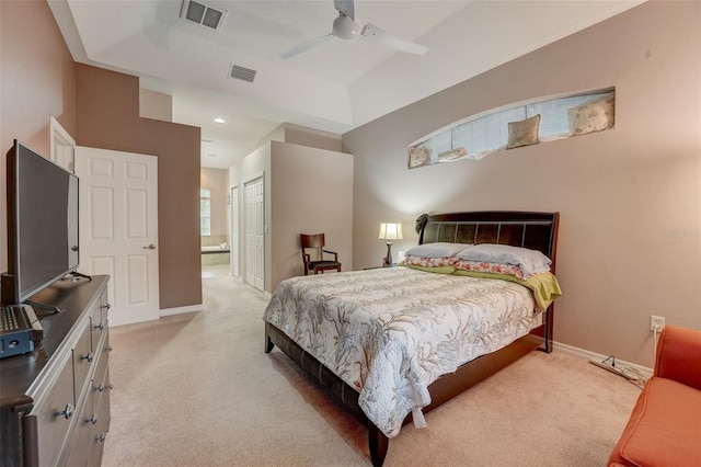 bedroom with ceiling fan, light colored carpet, ensuite bath, and a closet