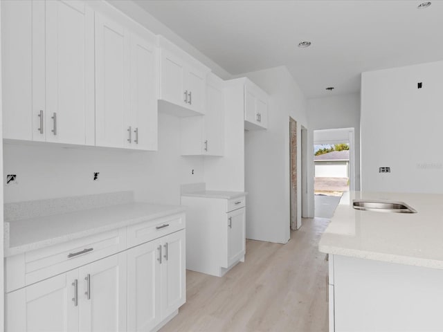 kitchen with white cabinets, sink, and light wood-type flooring