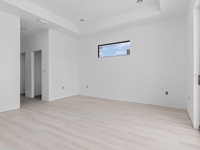 spare room featuring light hardwood / wood-style floors and a raised ceiling