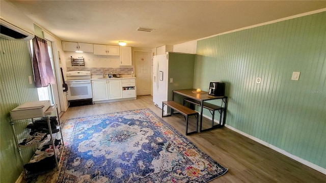 kitchen featuring sink, white cabinets, light hardwood / wood-style flooring, backsplash, and range