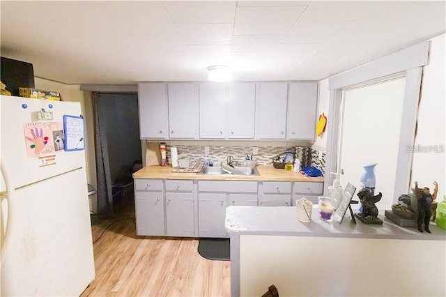 kitchen featuring sink, white fridge, gray cabinetry, light hardwood / wood-style flooring, and tasteful backsplash