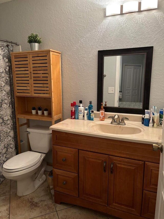 bathroom with toilet, large vanity, and tile flooring