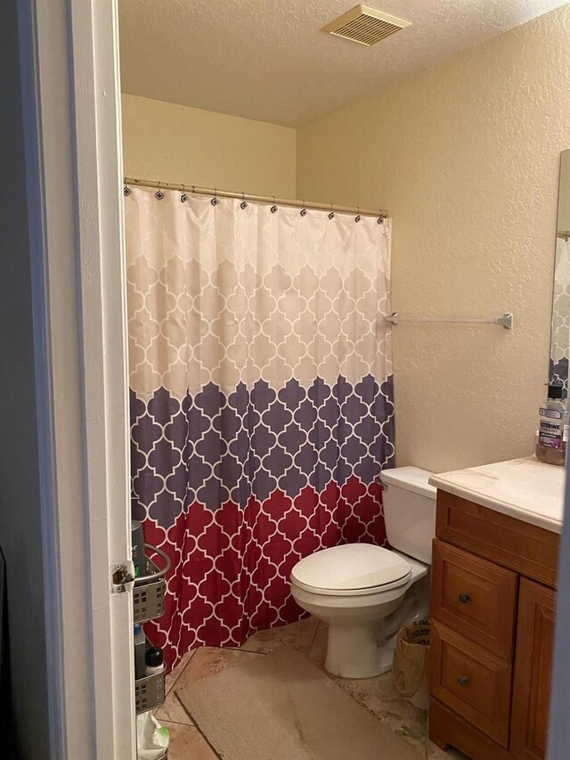 bathroom with toilet, tile floors, a textured ceiling, and vanity