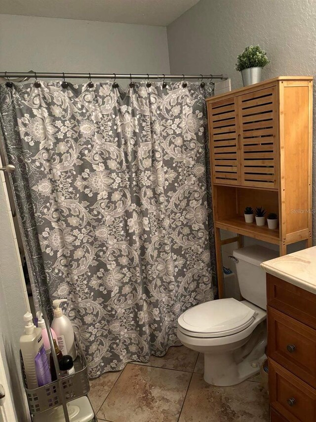 bathroom featuring toilet, tile floors, and vanity