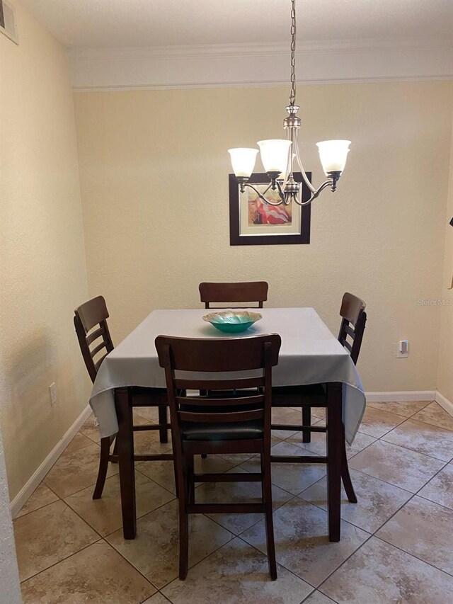 tiled dining room featuring ornamental molding and a chandelier