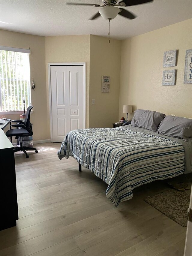 bedroom featuring a textured ceiling, a closet, ceiling fan, and light wood-type flooring