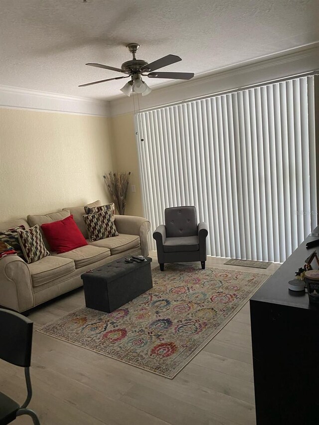 living room with ornamental molding, ceiling fan, and light wood-type flooring