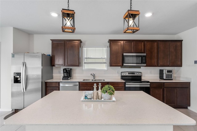 kitchen with appliances with stainless steel finishes, a kitchen island, hanging light fixtures, and sink