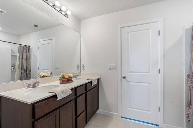 full bathroom with a textured ceiling, tile patterned flooring, a sink, visible vents, and double vanity