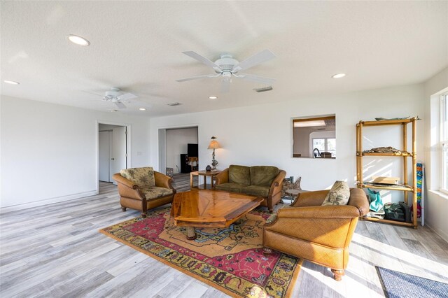 living room featuring light hardwood / wood-style floors, a textured ceiling, and ceiling fan