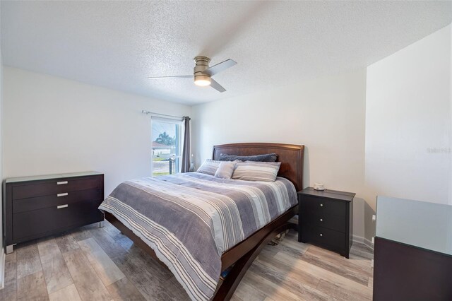 bedroom featuring a textured ceiling, light wood-type flooring, and ceiling fan