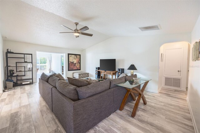 living room with light hardwood / wood-style floors, a textured ceiling, ceiling fan, and vaulted ceiling