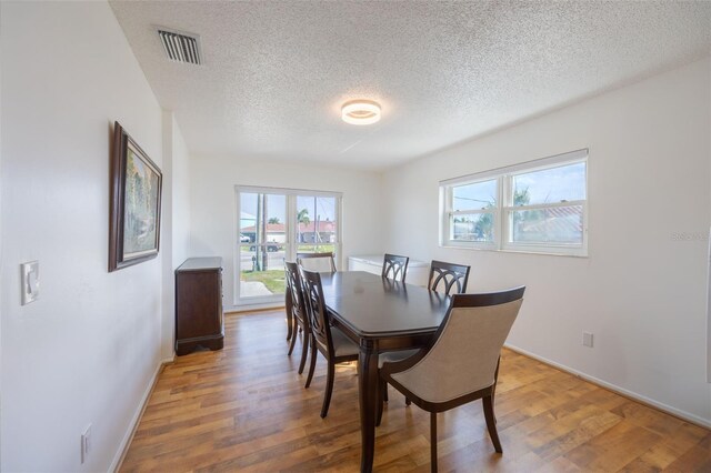 dining room with a textured ceiling and dark hardwood / wood-style flooring