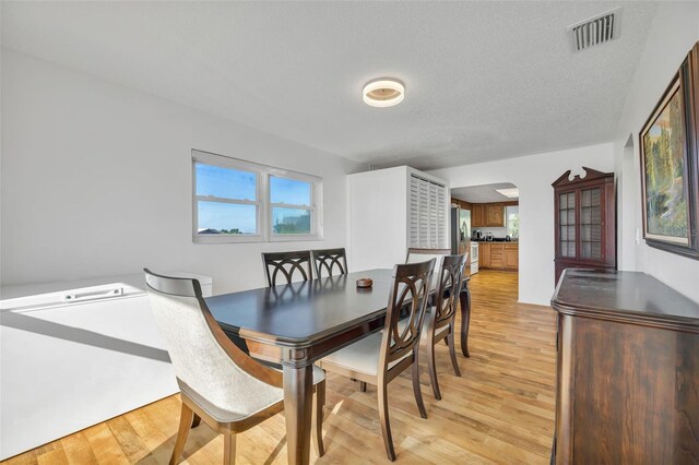 dining room featuring a textured ceiling and light wood-type flooring