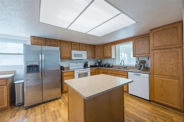 kitchen featuring a kitchen island, white appliances, sink, a textured ceiling, and light hardwood / wood-style floors