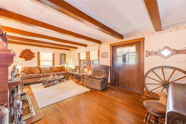 living room featuring crown molding, hardwood / wood-style flooring, a brick fireplace, and beam ceiling