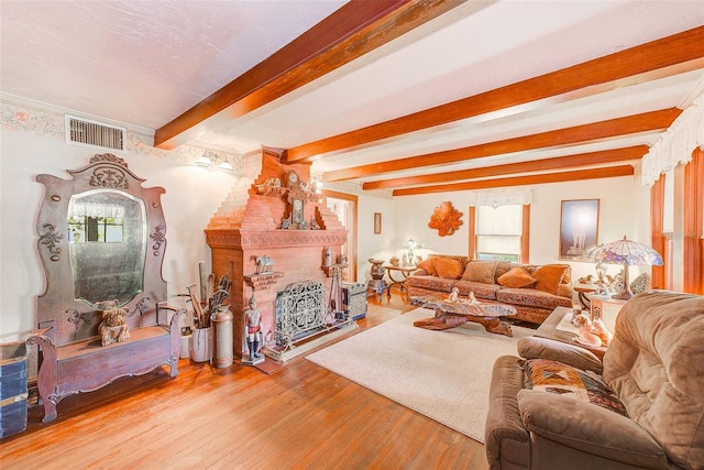 living room with a fireplace, wood-type flooring, beam ceiling, and a wealth of natural light