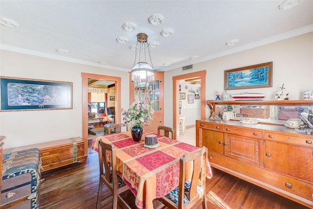 dining area with crown molding, dark wood-type flooring, and a textured ceiling