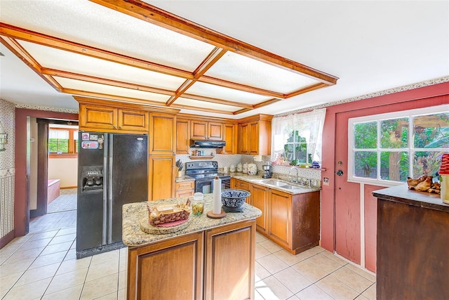 kitchen featuring light tile patterned floors, black appliances, a kitchen island, sink, and light stone countertops