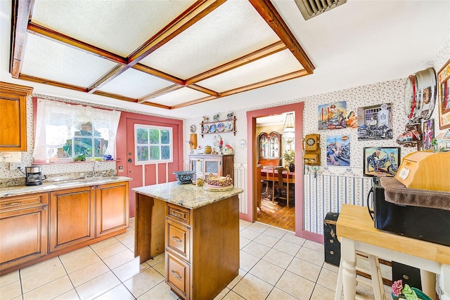 kitchen featuring light tile patterned floors, a kitchen island, light stone counters, and sink