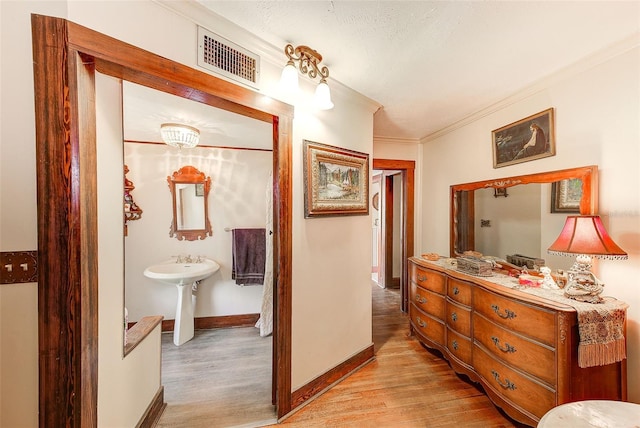 hall with crown molding, a textured ceiling, sink, and light hardwood / wood-style floors