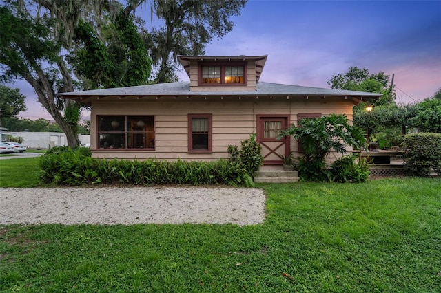 back house at dusk with a lawn