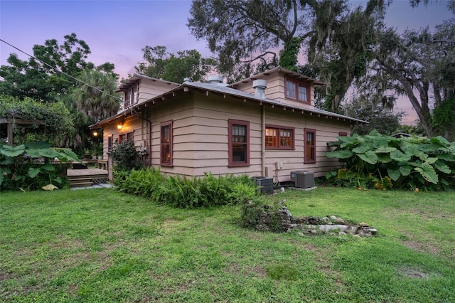 property exterior at dusk with a yard, a deck, and central air condition unit