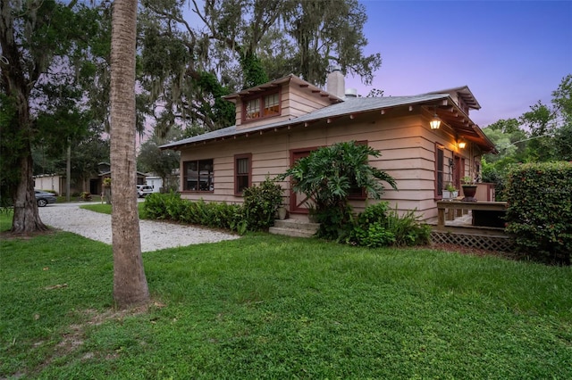 property exterior at dusk featuring a yard and a wooden deck