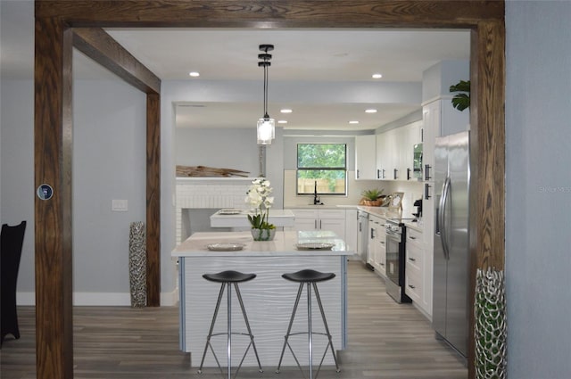 kitchen with decorative light fixtures, white cabinets, stainless steel appliances, and a kitchen bar