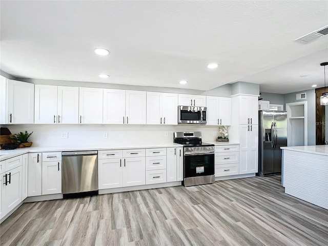 kitchen featuring appliances with stainless steel finishes, light hardwood / wood-style flooring, pendant lighting, and white cabinetry