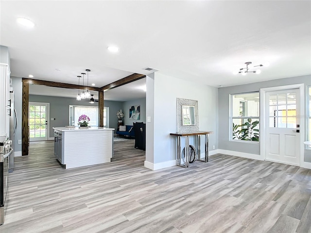 kitchen with a kitchen island, white cabinets, light hardwood / wood-style flooring, and pendant lighting