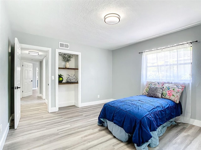 bedroom featuring a textured ceiling and light wood-type flooring