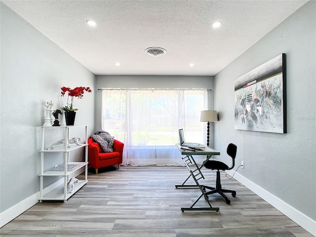 office with a textured ceiling and light hardwood / wood-style floors