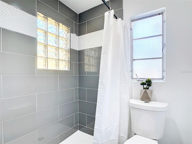 bathroom featuring a shower with shower curtain, plenty of natural light, and toilet