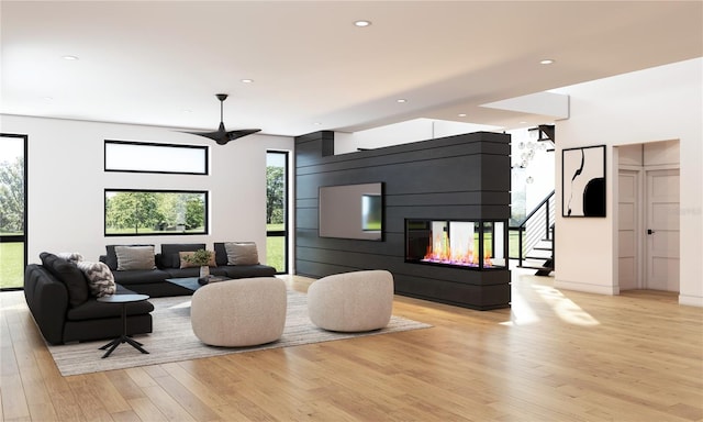 living room with ceiling fan, a multi sided fireplace, and light hardwood / wood-style flooring