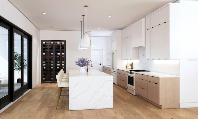 kitchen with light hardwood / wood-style floors, decorative light fixtures, white cabinetry, white range, and a kitchen island with sink