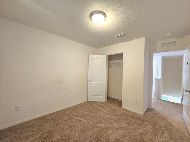 unfurnished bedroom featuring light carpet, a closet, and a textured ceiling