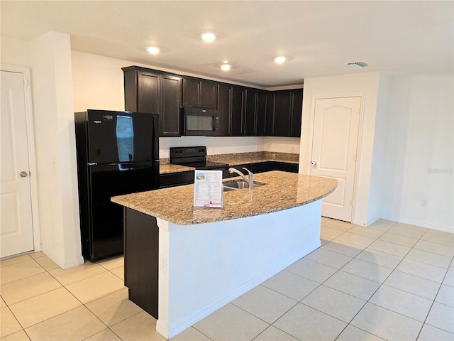 kitchen featuring a kitchen island with sink, light stone counters, light tile patterned floors, sink, and black appliances