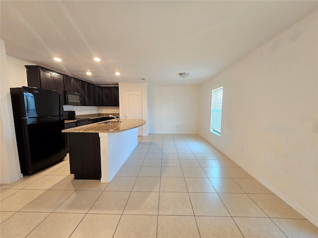 kitchen featuring black appliances, a center island with sink, light stone counters, and light tile patterned floors