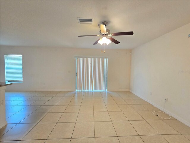 tiled empty room featuring ceiling fan