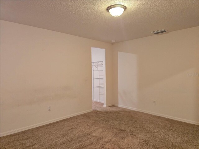 unfurnished room featuring a textured ceiling and light colored carpet