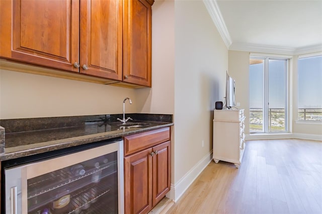 bar with dark stone counters, wine cooler, ornamental molding, sink, and light wood-type flooring