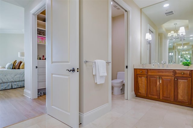 bathroom with toilet, a notable chandelier, vanity, and wood-type flooring