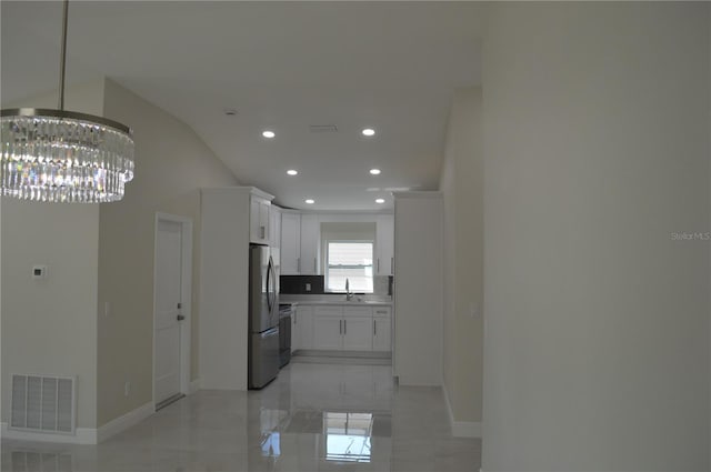 corridor with vaulted ceiling, light tile floors, sink, and an inviting chandelier