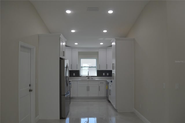 kitchen with light tile floors, sink, white cabinetry, and stainless steel refrigerator