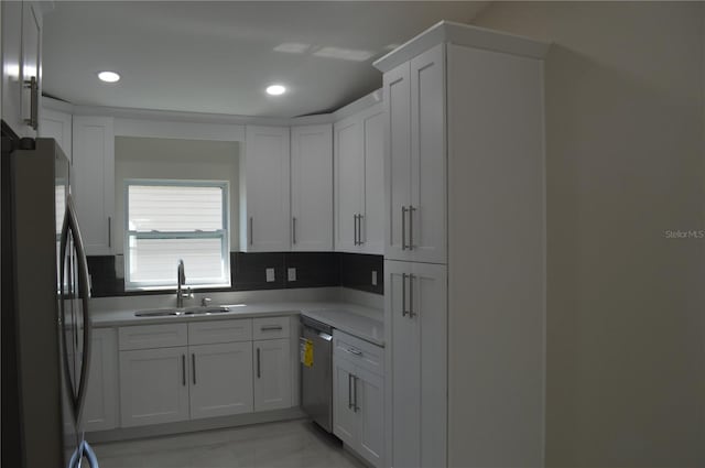 kitchen with black refrigerator, white cabinetry, backsplash, sink, and stainless steel dishwasher