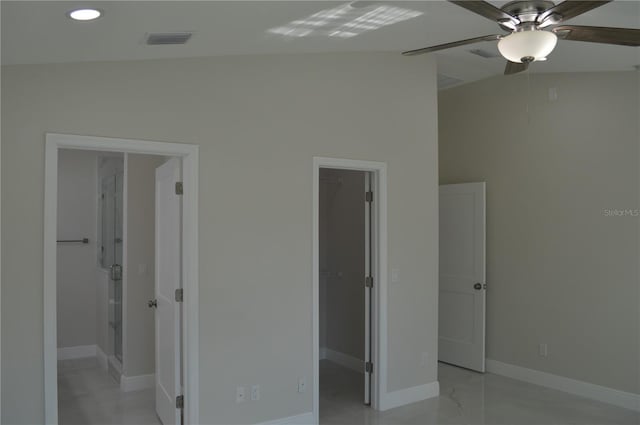 unfurnished bedroom with a closet, lofted ceiling, ceiling fan, light tile floors, and a spacious closet