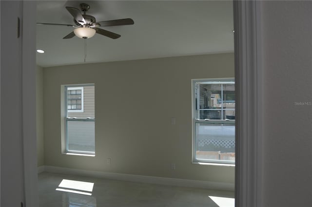 unfurnished room featuring light tile flooring, ceiling fan, and a wealth of natural light